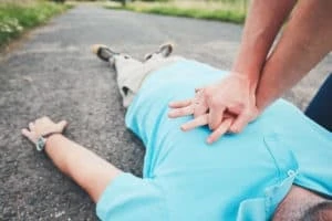Wer Erste Hilfe leistet, rettet Leben! Jemand führt eine Herzdruckmassage, bei einer Person die auf dem Boden liegt, aus