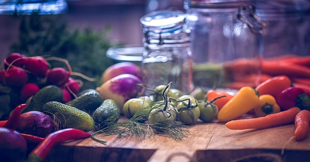 Verschiedene Gemüsesorten und Einmachgläser auf einem Tisch