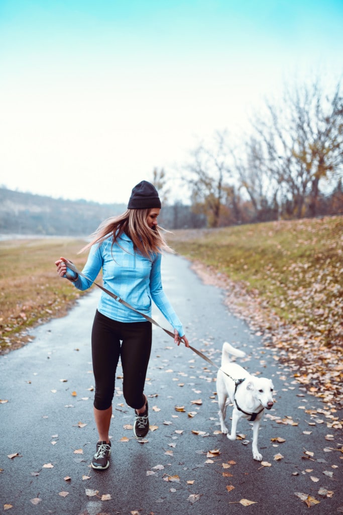 Frau joggt mit einem Hund im Park