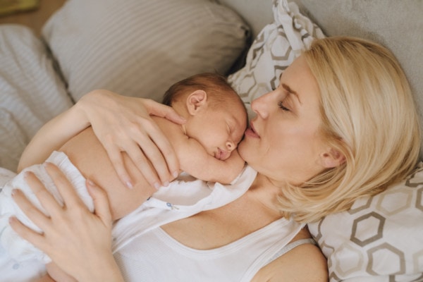 Während des Wochenbettes hält eine Frau ihr Baby im Arm