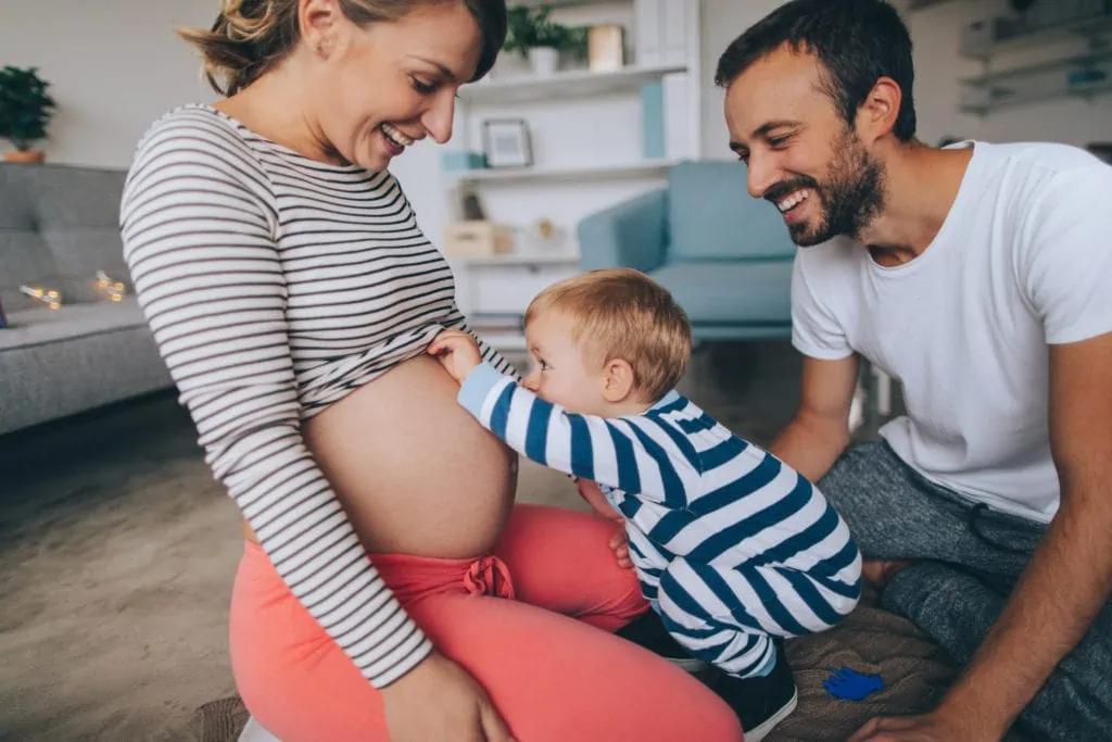 Eine Familie unterhält sich spielerisch über die körperlichen Veränderungen in der Schwangerschaft