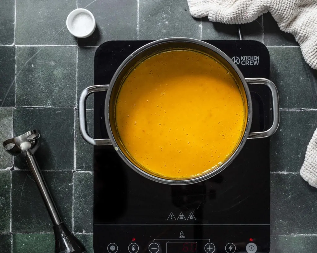 Im Topf sieht man die fertige Kürbissuppe mit Orangensaft und Kokosmilch.