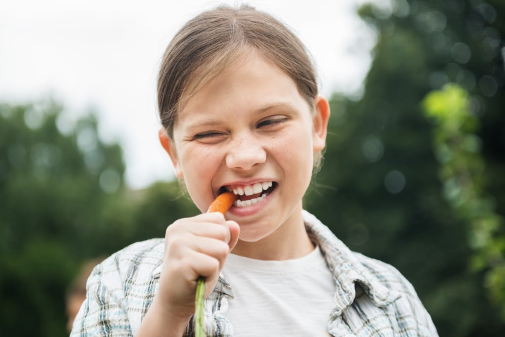 Junges Mädchen isst eine Karotte für das Immunsystem