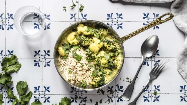 In einem Topf ist das Blumenkohl-Brokkoli-Curry mit roten Linsen und Reis serviert.