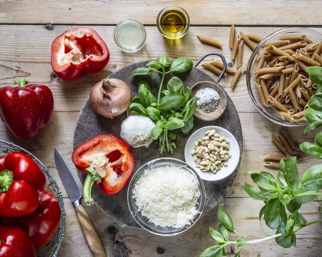 Alle Zutaten für die geröstete Paprika Pasta liegen auf und neben einem Brett.