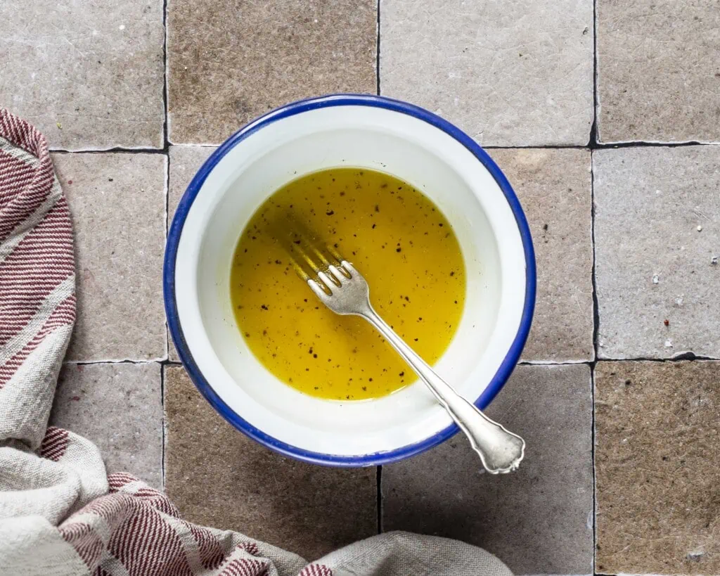 In einer Schüssel befindet sich das Dressing aus Olivenöl, Orangensaft, Honig, Apfelessig, Salz und Pfeffer.