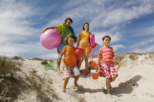 Reiseapotheke: Checkliste für deinen Trip. Eine Familie auf dem Weg zum Strand - dank der Reiseapotheke-Checkliste sind sie bestens vorbereitet