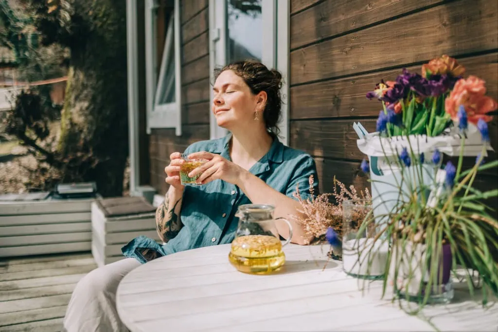 Eine Frau entspannt mit einer Tasse Tee auf der Veranda - sie weiß, was sie bei einem Tinnitus tun muss