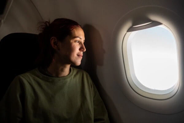 Druckausgleich im Flugzeug Eine junge Frau schaut aus dem Flugzeugfenster - sie praktiziert den Druckausgleich im Flugzeug