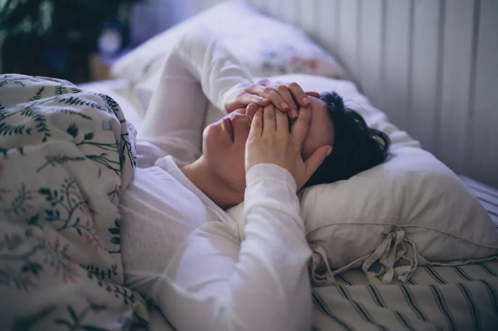 Eine Frau liegt im Bett und kann wegen Schlafapnoe nicht schlafen