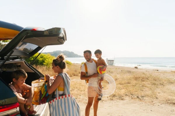 Sonnenstich vorbeugen Eine Familie auf dem Weg zum Strand - sie wissen, wie sie einem Sonnenstich vorbeugen